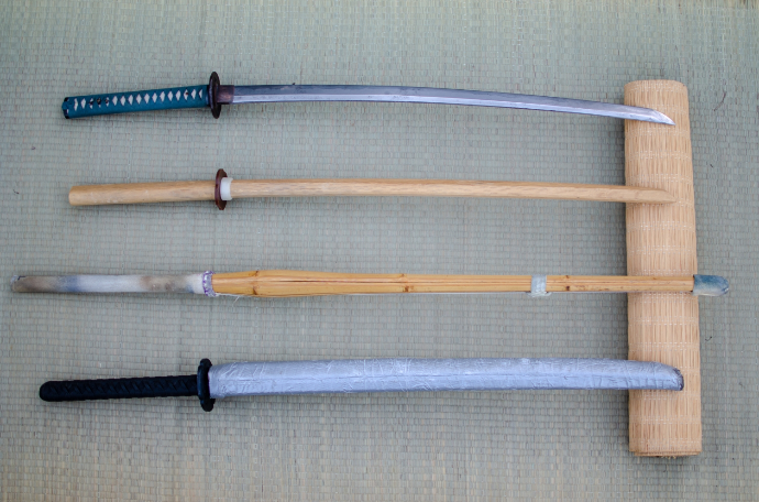 Různé druhy zbraní v našem dojo. Gekikentó (dole) odpovídá meči více, než kendistický shinai (druhý odspoda)